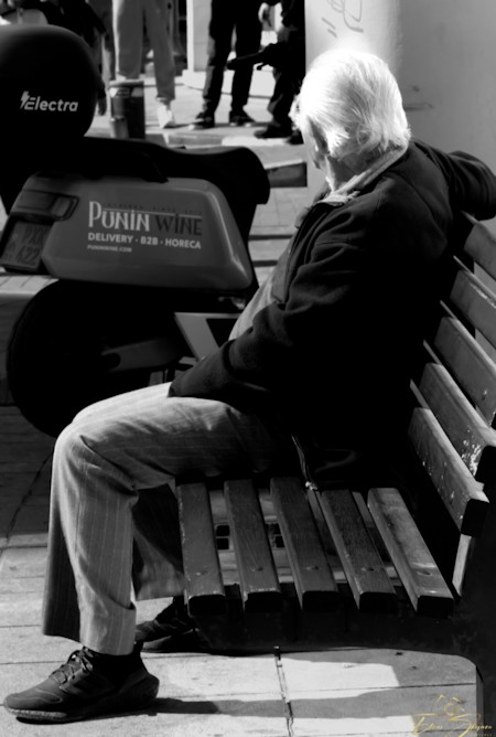 Black and White Street Photography of an Elderly Man Sitting on a Bench