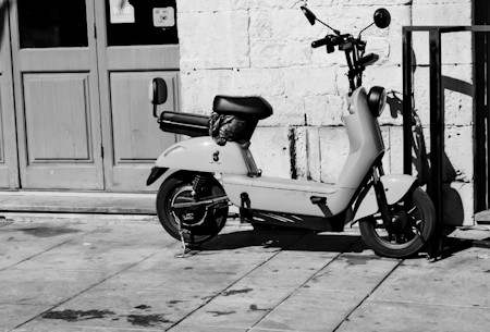Black and White Street Photography of an Electric Scooter Parked on a City Street