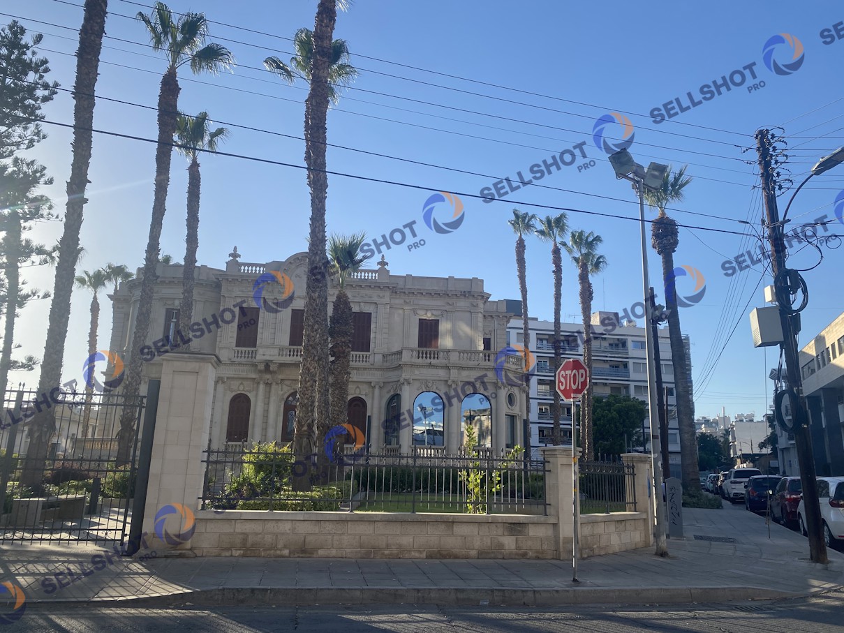 Historic Old Library building in Limassol, Cyprus, with palm trees and urban street surroundings.