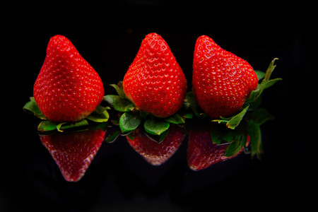 Three strawberries against a black background