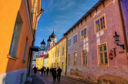 A narrow cobblestone street in the Old Town of Tallinn, Estonia, with the  domes of the Alexander Nevsky Cathedral ahead