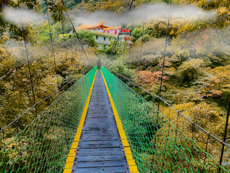 A suspension bridge overlooking the gorge and leading up to a trail and Changuang Temple Bell Tower